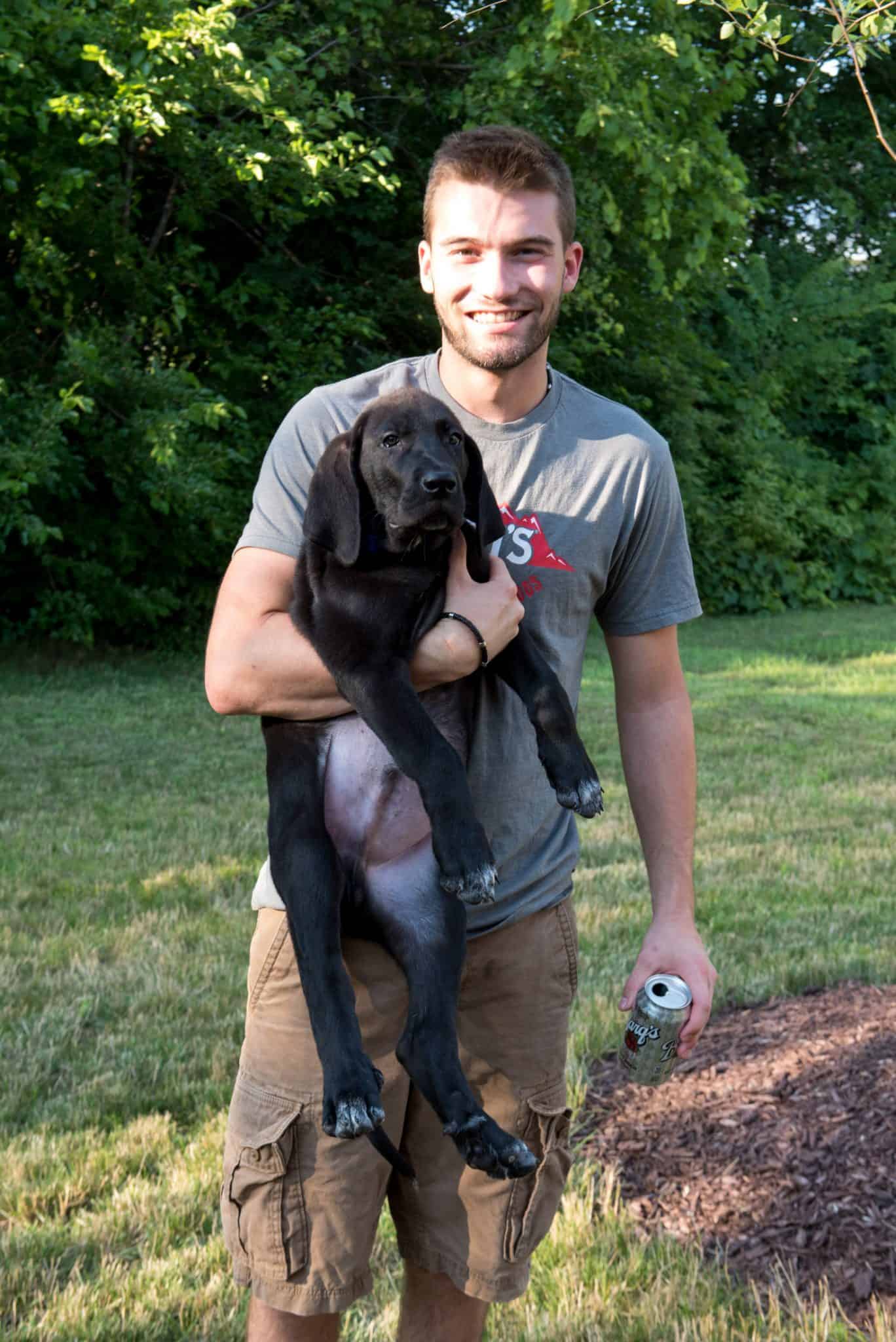 Apex employee holding Roman the black lab puppy