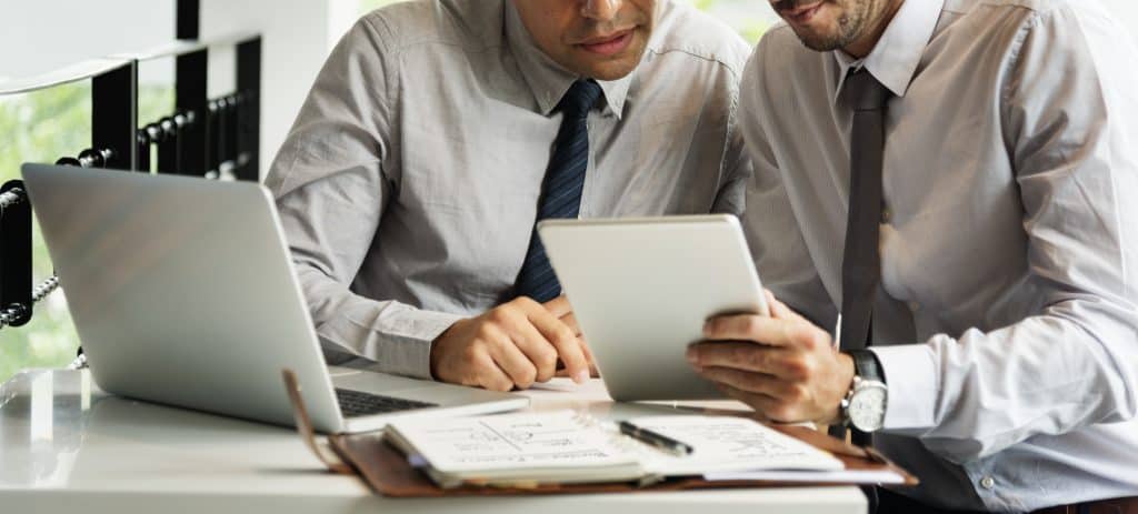 Two men consulting each other over a supplies report
