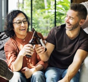 A woman and man clink glasses while laughing