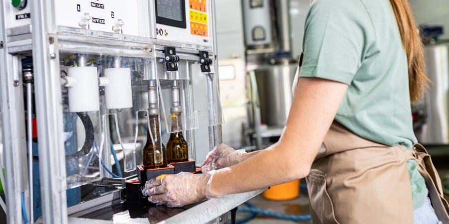 Woman using automatic filler for beer bottles