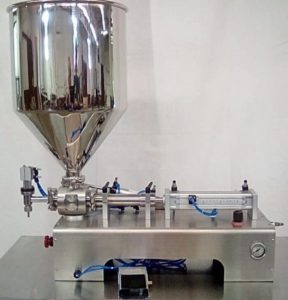 Semi-automatic tabletop piston filler positioned against a wall